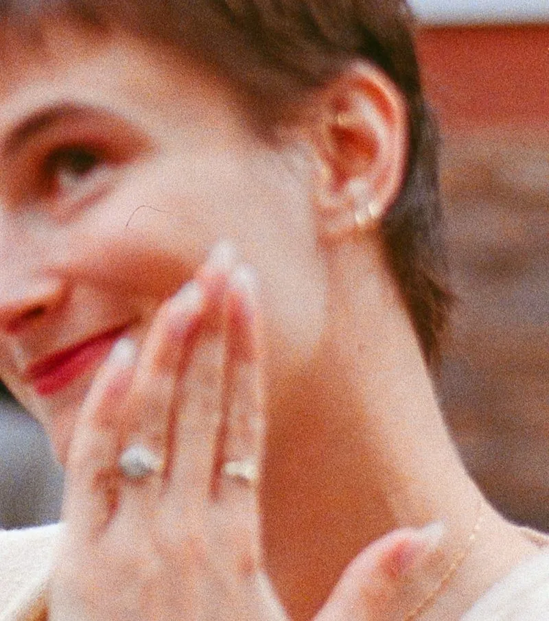 Celia&rsquo;s hand at her cheek, ring on her finger